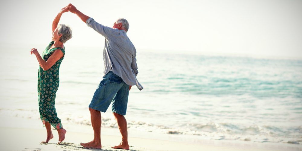 An elderly couple dancing on the beach | Medicare Supplement | Midwest Employee Benefits